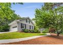Charming home with grey painted brick, and an attached garage, surrounded by lush greenery at 4774 Olde Village Ln, Atlanta, GA 30338