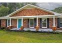 Inviting brick home showcasing a charming front porch with columns and a blue front door at 599 Honey Creek Rd, Conyers, GA 30094
