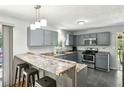 Well-lit kitchen featuring gray cabinets, a breakfast bar with seating, and modern stainless steel appliances at 173 Avalon Way, Riverdale, GA 30274