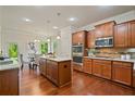 Modern kitchen with stainless steel appliances, custom cabinets, granite counters, and an adjacent dining area at 6805 Bransford Dr, Cumming, GA 30040