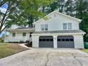 Inviting two-story home with a two-car garage, white siding, a covered porch, and mature trees at 3045 Revere Cir, Snellville, GA 30039