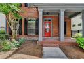 Inviting front porch with brick columns, a red door, and manicured landscaping at 375 Causeway Ct, Suwanee, GA 30024