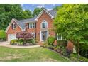 Attractive brick home featuring lush landscaping, a manicured lawn, and mature trees for added privacy at 420 Windswept Ct, Roswell, GA 30075
