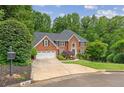 Beautiful brick home with manicured landscaping and mature trees surrounding the property on a cul-de-sac at 420 Windswept Ct, Roswell, GA 30075