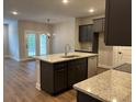 Open-concept kitchen featuring an island with a sink, granite countertops, stainless steel appliances, and dark cabinets at 2409 Malster Ln, Lawrenceville, GA 30043