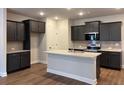Modern kitchen boasts granite countertops, stainless steel appliances, stylish cabinetry, and wood flooring at 2409 Malster Ln, Lawrenceville, GA 30043