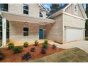 Close-up of a home's exterior showcasing landscaping, a brick facade, and a bright blue door at 3902 Bouldercrest Se Rd, Ellenwood, GA 30294
