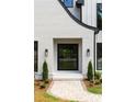 Modern black framed glass front door with stone paver entry way and trimmed bushes at 4091 Oak Forest Ne Dr, Brookhaven, GA 30319