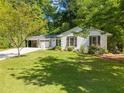Well-maintained single-story home with white brick, a manicured lawn, and mature trees providing shade at 3176 Gablewood Ct, Decatur, GA 30033