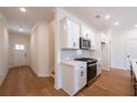 Bright kitchen featuring white cabinets, stainless steel appliances, and hardwood floors at 405 Carrera Ln, Acworth, GA 30102