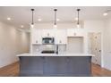 Open kitchen with a gray island, white cabinets, modern appliances, and stylish pendant lighting at 405 Carrera Ln, Acworth, GA 30102
