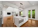 White kitchen with island gas range and open-concept design to the living room and fireplace; natural light at 9179 Selborne Ln, Chattahoochee Hills, GA 30268
