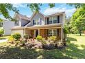 Two-story home with gray siding, black shutters, brick accents, and a colorful, landscaped front yard at 4065 Waters End Ln, Snellville, GA 30039