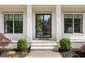 Elegant front door with black trim flanked by windows and manicured landscaping, enhancing curb appeal at 304 Meadowbrook Ne Dr, Atlanta, GA 30342