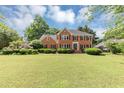 Beautiful brick home with a well-manicured lawn, dark shutters, and lovely landscaping offers classic curb appeal at 395 Clubfield Dr, Roswell, GA 30075