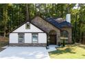 Beautiful home with stone and white facade, arched entryway, and a well-kept lawn in a wooded setting at 3563 Brenda Ct, Douglasville, GA 30135