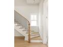 Elegant staircase with a wooden banister and black iron spindles with natural light at 11536 Serenbe Ln, Chattahoochee Hills, GA 30268
