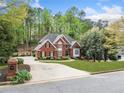 Spacious brick home with a large driveway, green lawn, and mature trees, offering a serene and private setting at 250 Chason Wood Way, Roswell, GA 30076