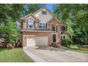 Attractive two-story brick home with a two-car garage, complemented by a manicured lawn and mature trees at 300 Wesfork Nw Way, Suwanee, GA 30024