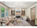Elegant living room boasts a stone fireplace, built-in bookshelves, and large windows for plenty of natural light at 306 Nottaway Ln, Alpharetta, GA 30009