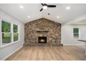 Cozy living room features a stone fireplace, ceiling fan, recessed lighting and wood-look flooring at 3952 Leisure Se Ct, Conyers, GA 30013