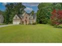 Traditional two-story home with a brick facade, lush green lawn, mature trees, and a two-car garage at 4942 Brown Leaf Dr, Powder Springs, GA 30127