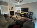 Cozy living room with a fireplace, ceiling fan, and large windows for natural light at 135 Governors Rdg, Auburn, GA 30011