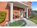 Cozy front porch with chairs, plants, and a decorative wreath, complemented by manicured landscaping at 988 Treymont Way, Lawrenceville, GA 30045