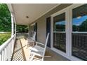 Relaxing front porch area with classic white rocking chairs and nice view of the front yard at 130 Lacey Oak Ln, Loganville, GA 30052