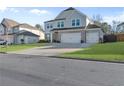 Exterior view of home showing three-car garage, grey siding, manicured lawn, and neighborhood at 3560 Summerpoint Xing, Cumming, GA 30028