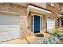 Townhome entry with blue door, white trim, front garden, and attached garage at 5019 Lower Elm St, Atlanta, GA 30349