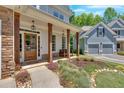 Charming front porch with stone columns, wood door, bench and landscaped walkway at 209 Wildwood Way, Canton, GA 30114