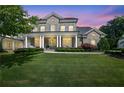 Elegant two-story brick home featuring a well-manicured lawn and a stately front porch illuminated at twilight at 3264 Andante Ne Dr, Marietta, GA 30062