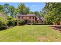 Traditional brick home with a lush green lawn, mature trees, and manicured hedges at 5124 Vermack Rd, Dunwoody, GA 30338