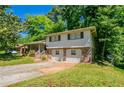 Exterior view of split-level home with a two-car garage, front porch, and mature trees at 802 San Miguel Dr, Stone Mountain, GA 30083