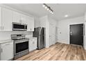 Modern kitchen boasts stainless steel appliances, white cabinets, stone counters, subway tile backsplash, and wood-look flooring at 525 Parkway Ne Dr # 110, Atlanta, GA 30354