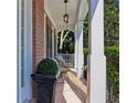 Inviting covered front porch with brick flooring, white columns, and comfortable seating at 7014 E Hills Way, Woodstock, GA 30189