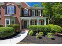 Close-up of brick home's entrance featuring a covered porch with white columns and manicured landscaping at 7014 E Hills Way, Woodstock, GA 30189
