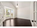 Bright living room boasts large windows, hardwood floors, french doors, and vaulted ceiling at 6995 Tybridge St, Cumming, GA 30040