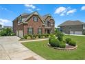 Well-maintained brick home with lush landscaping, showcasing a driveway and a detached garage at 2520 Wood Fern Ln, Cumming, GA 30041