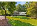 Picturesque front yard with a verdant lawn, mature trees, and a charming home with covered porch at 1150 Kennesaw Due West Nw Rd, Kennesaw, GA 30152