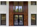 Elegant entryway features a modern steel and glass front door, and white brick with wood accents at 4 Bentley Trace Mnr, Atlanta, GA 30327