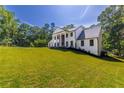 View of the house from a distance showcasing the front yard, white brick, black trim and mature trees at 4 Bentley Trace Mnr, Atlanta, GA 30327