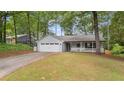 Well-kept single-story home with attached garage, appealing front porch, and lush green lawn surrounded by mature trees at 4771 Pinefield Nw Dr, Acworth, GA 30102