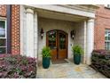 Stately stone entrance with arched double wood doors, lantern sconces, and lush potted ferns create a welcoming approach at 351 Ne Washington Ne Ave # 307, Marietta, GA 30060