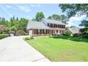 Brick home with attached garage, lush front lawn, mature trees, and long driveway at 5199 Beech Forest Sw Dr, Lilburn, GA 30047