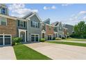 View of townhomes, each with an attached garage and manicured lawn at 5221 Sherwood Way, Cumming, GA 30040