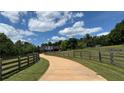 Spacious driveway leads to a beautiful home surrounded by lush greenery and wooden fences at 5945 Bannister Rd, Cumming, GA 30028