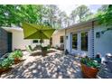 Inviting outdoor patio features a stone surface, dining set with umbrella, and lush potted plants at 2298 Pembrook Pl, Atlanta, GA 30324