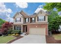 Attractive two-story home featuring a brick and siding exterior, mature trees, and a two-car garage at 139 Lake Reserve Way, Canton, GA 30115